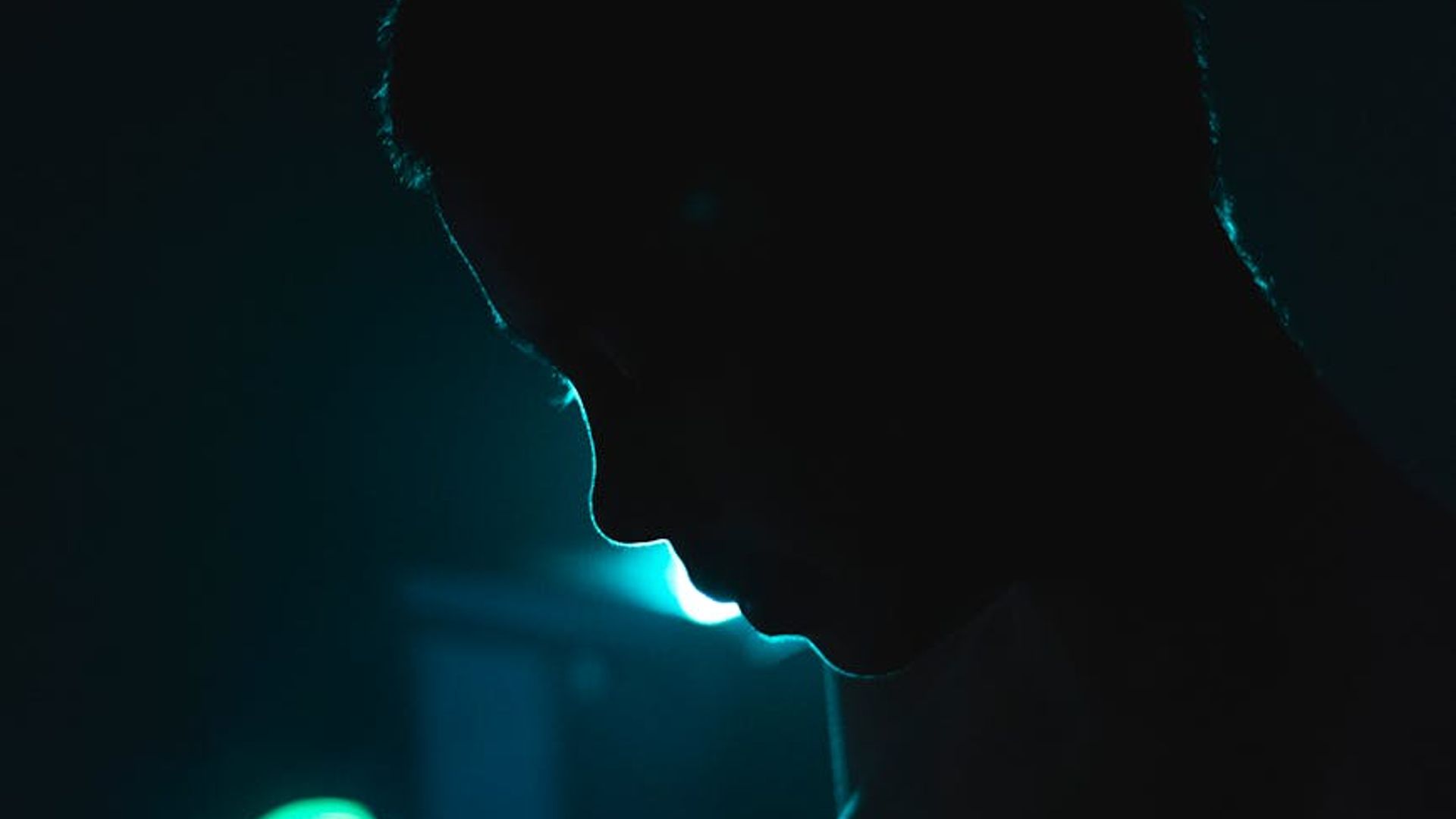 Person practicing yoga in a dark room with cyan neon lighting